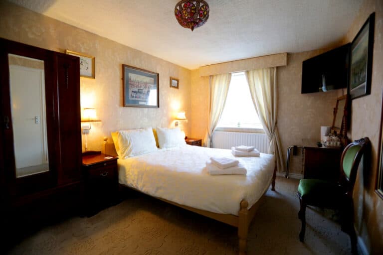 This image shows a king bed, pictures on the wall, window to the right