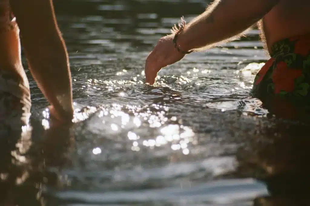 2 people are standing in open water, with ripples and sunshine reflecting the mood