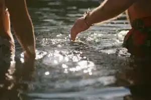 2 people are standing in open water, with ripples and sunshine reflecting the mood